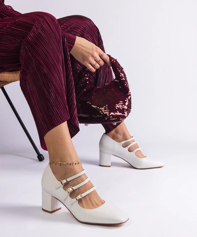 Białe czółenka na słupku z ozdobnymi sprzączkami Izida